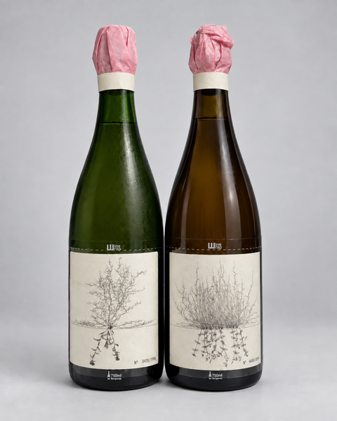 Two-bottle wine collection with original pink tissue wrappers; wine identities awaiting confirmation. 淺灰色無縫背景，中性打光。4:5。